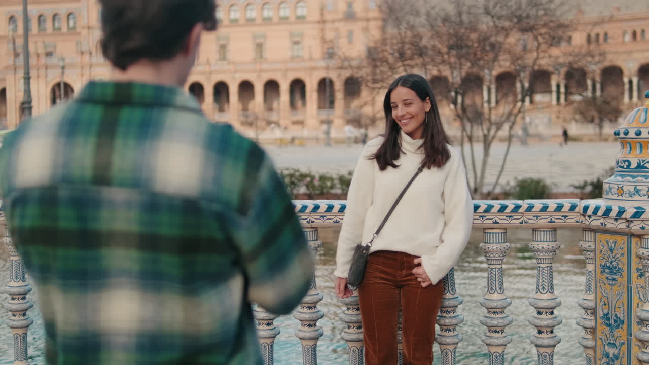 Young man taking photo of his girlfriend on mobile phone