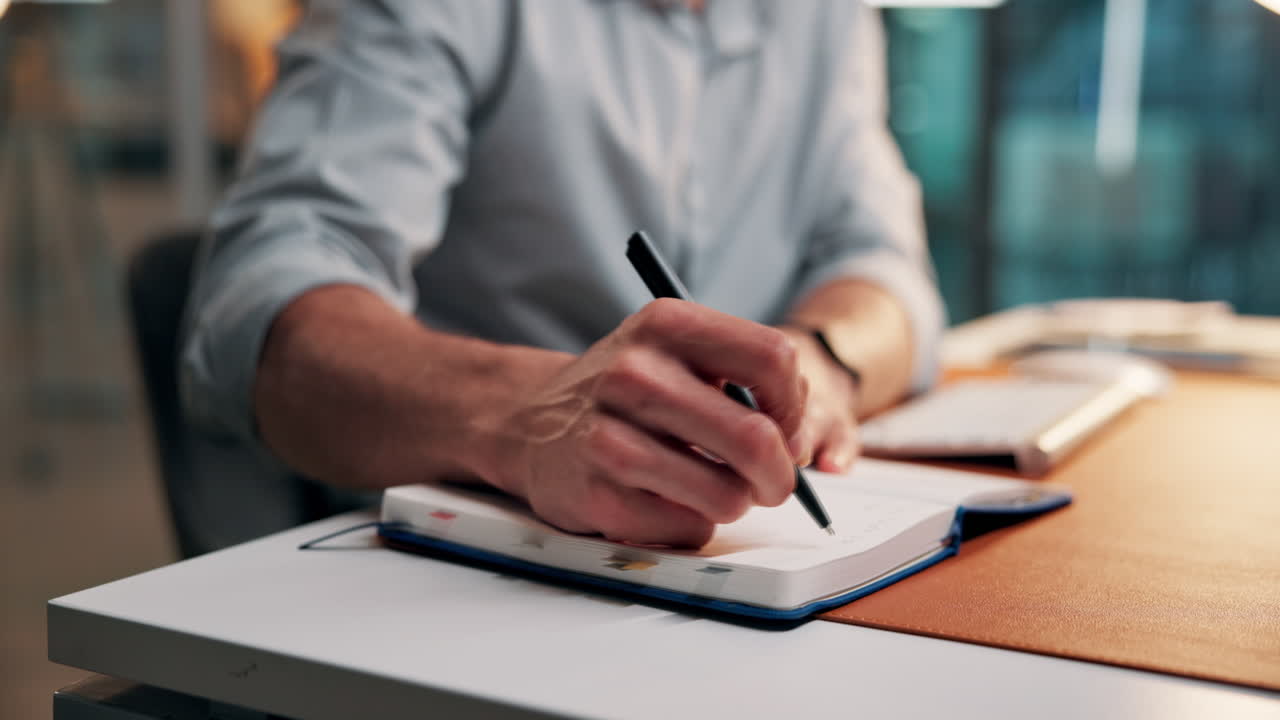 Close-up of Man's Hands Writing Notes in a Notebook