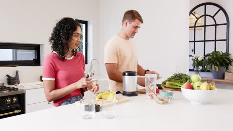 preparing healthy meal, young multiracial couple cutting fruits and vegetables in kitchen, at home