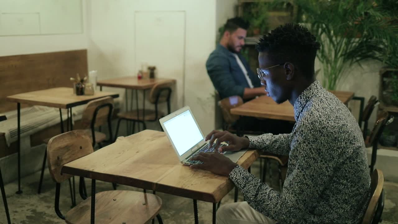 Giovane freelance afroamericano che usa il laptop in caffetteria