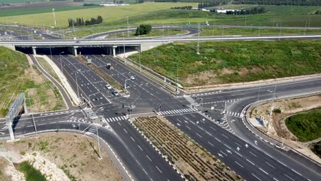 aerial forward drone shot of a multiple directions highway junction, surrounded by grass end trees