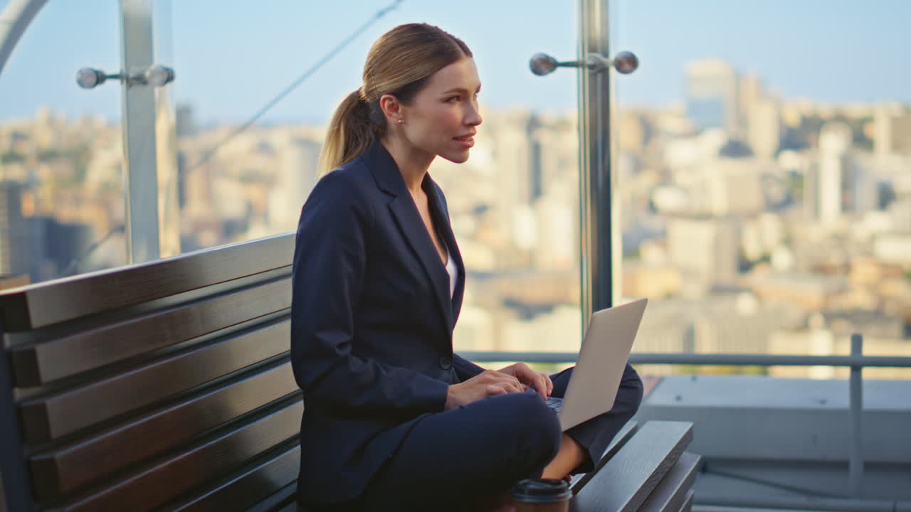 Manager creativo che digita al computer su una terrazza. Donna sorridente e ispirata che lavora da remoto.