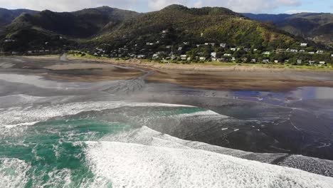 arroyo que fluye hacia el mar de tasmania en la pintoresca playa de piha de arena negra, antena