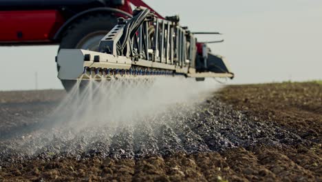 primer plano de un agricultor rociando suelo en una campaña agrícola desde una maquinaria roja