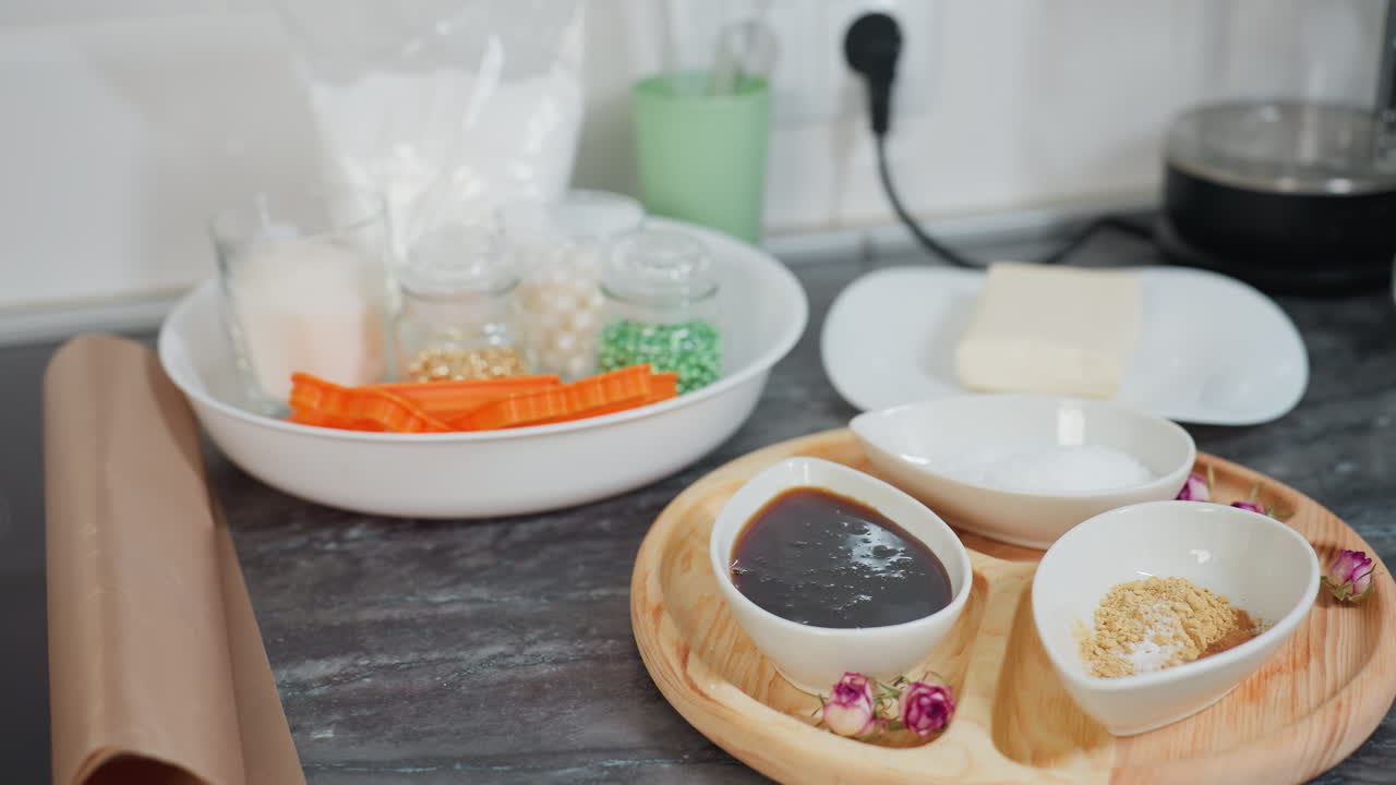 소스와 설탕으로 가득 찬 세라 그, 다채로운 재료가 들어있는 유리 항아리, 접시에 버터, 베이킹 도구 및 유리 비가있는 목조 트레이를 특징으로하는 현대 주방 도구의 클로즈업