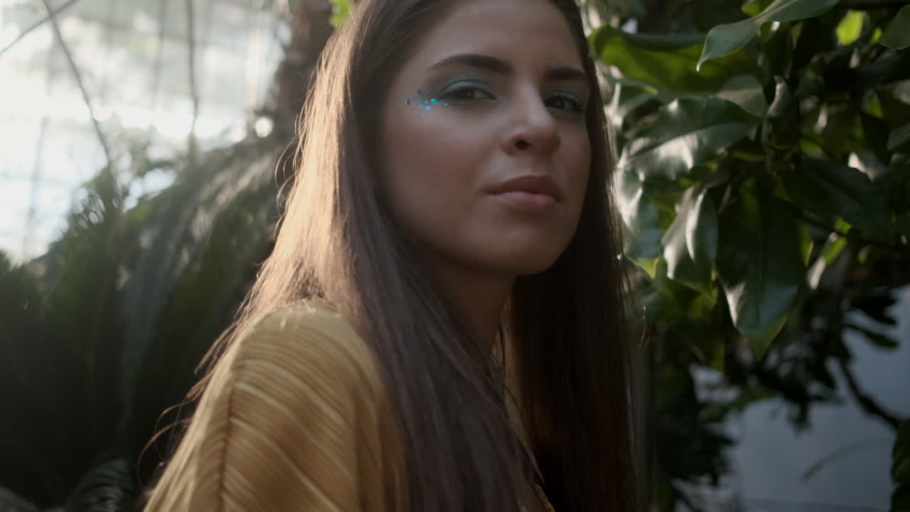 joven modelo mirando a la cámara en un invernadero tropical