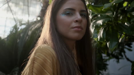 young girl model looking at camera in tropical greenhouse