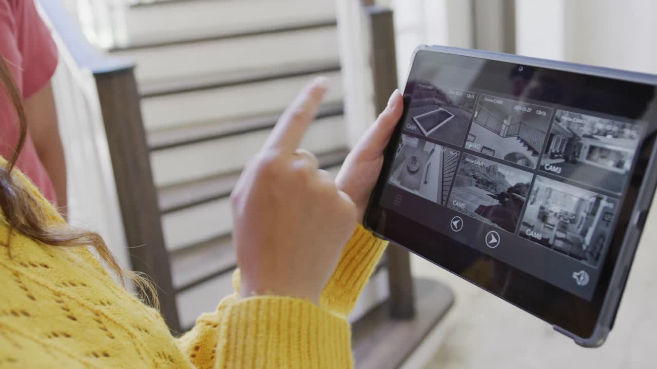 mujer biracial que pasa tiempo en casa usando una tableta con interfaz de cámara