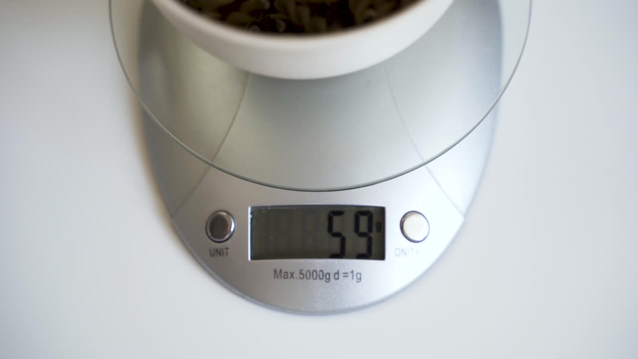 Digital scale display numbers changing while weighing bowl with pasta