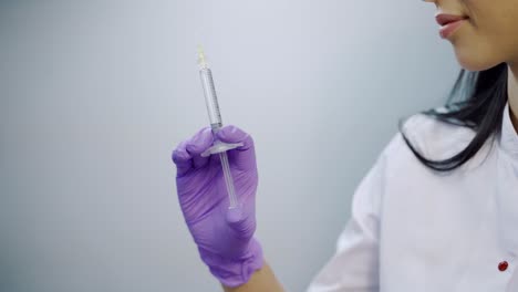 a beautician in purple gloves is holding an injection of a botulinum toxin in her hand at a medical cosmetology center. close-up. preparation to the procedure