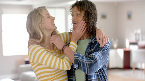 Portrait-of-happy-diverse-couple-embracing-and-playing-at-home,-slow-motion