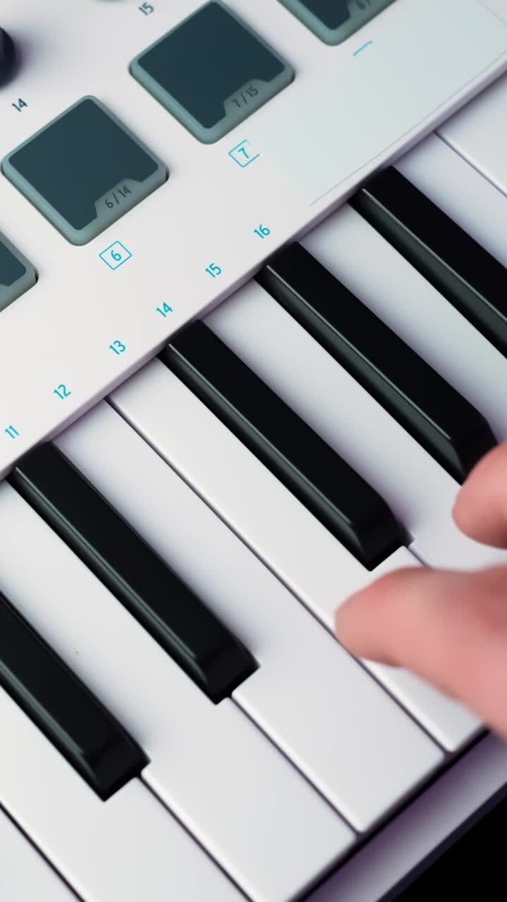 Close-up of a finger playing a melody on a white MIDI keyboard controller, soft shallow focus in a home studio, vertical