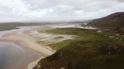 aerial footage over a beach and rolling hills on a sunny day in donegal, ireland