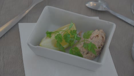 small plate with french petit apetizer, peace of lemon with koriander and tuna