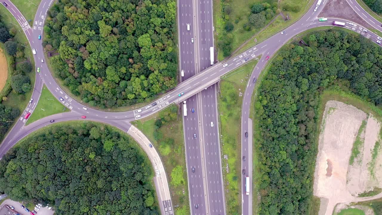 Birdseye drone aerial view following the motorway over a busy junction with a forwards motion