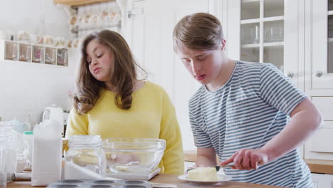 Junges-Down-Syndrom-Paar-Fügt-Butter-Zum-Kuchenrezept-Hinzu,-Das-Sie-Zu-Hause-In-Der-Küche-Backen