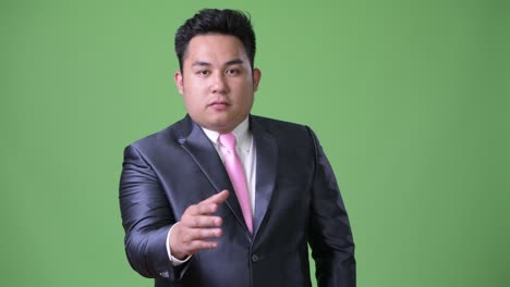 초록색 배경에 젊은 잘생긴 과체중 아시아 사업가