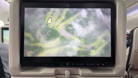 In-flight-infotainment-shows-clouds,-buildings,-road,-fields-during-flight