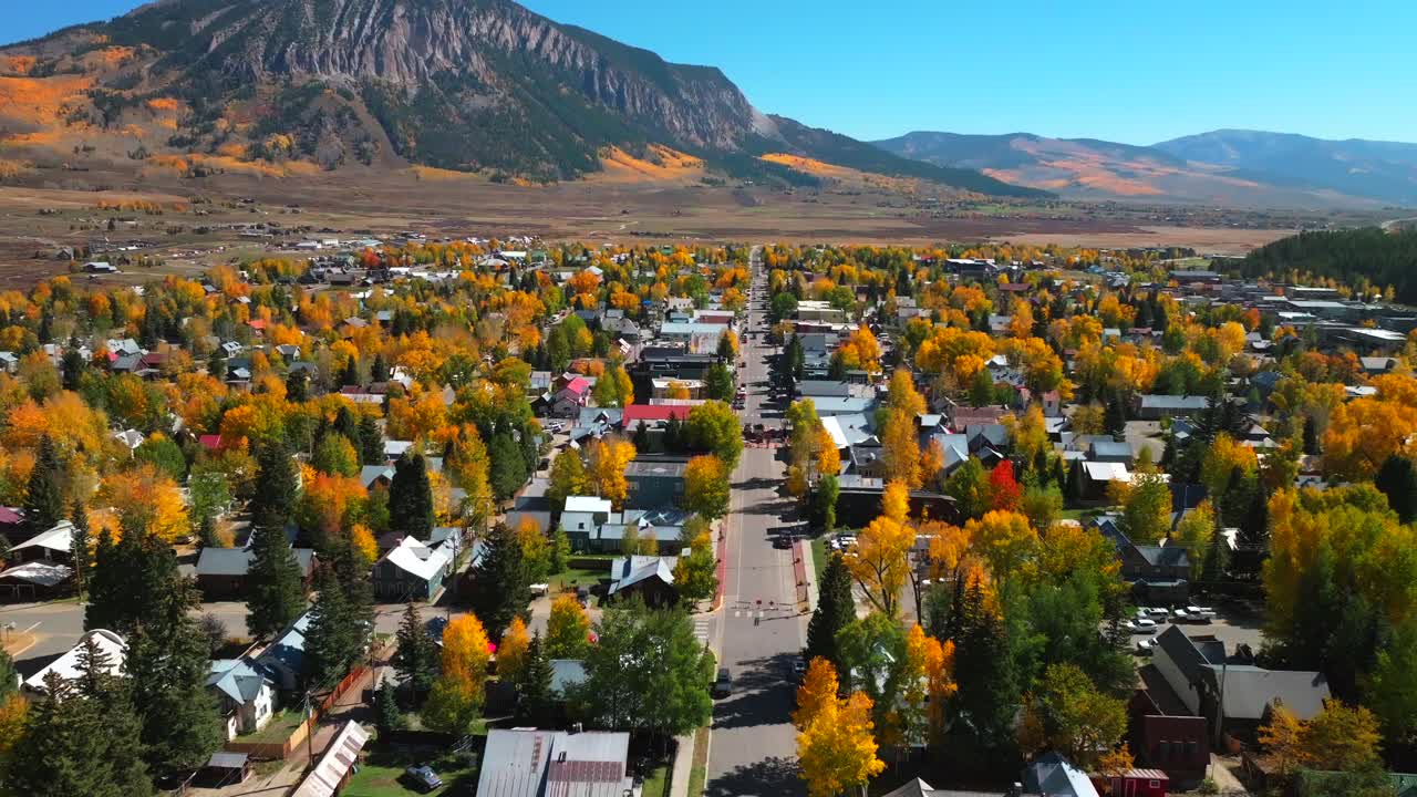 Main street Mount Crested Butte mountain town ski resort Kebler Ohio Pass aerial drone Colorado morning vibrant Aspen Trees fall autumn peak colors Gunnison National forest sunny blue sky forward pan