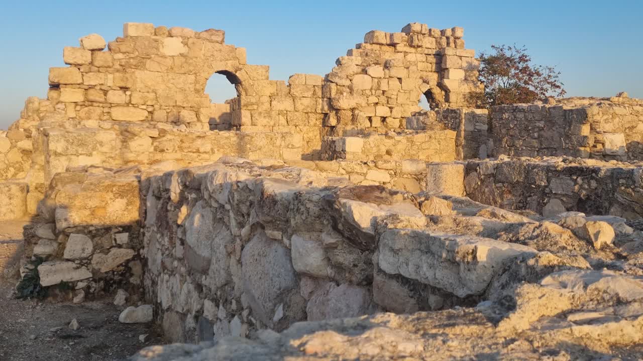 Evening sunlight illuminates ancient stone walls and ruins at Jabal al-Qal'a, Amman Citadel, Jordan, highlighting the historic layers and warm golden tones of this open-air site