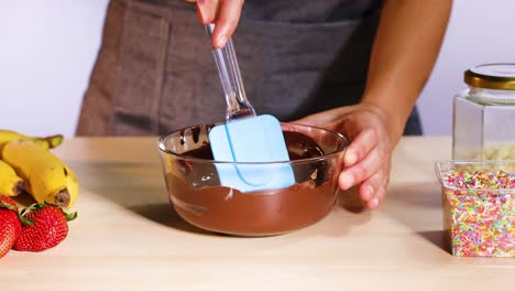 mezclando chocolate con espátula, rodeado de frutas