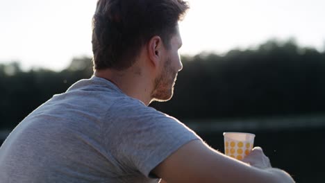 Video-of-pensive-man-sitting-by-the-lake-during-sunset