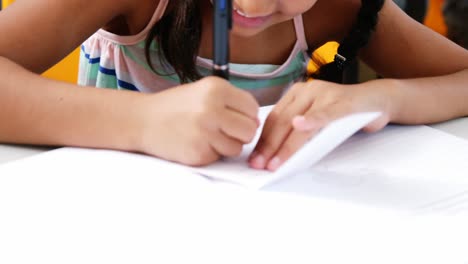 schoolgirl writing on chit in classroom