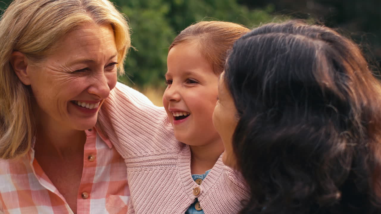 두 성숙 한 엄마 가 시골 에서 산책 하는 딸 을 품고 있는 동성 가족 의 포트레이트