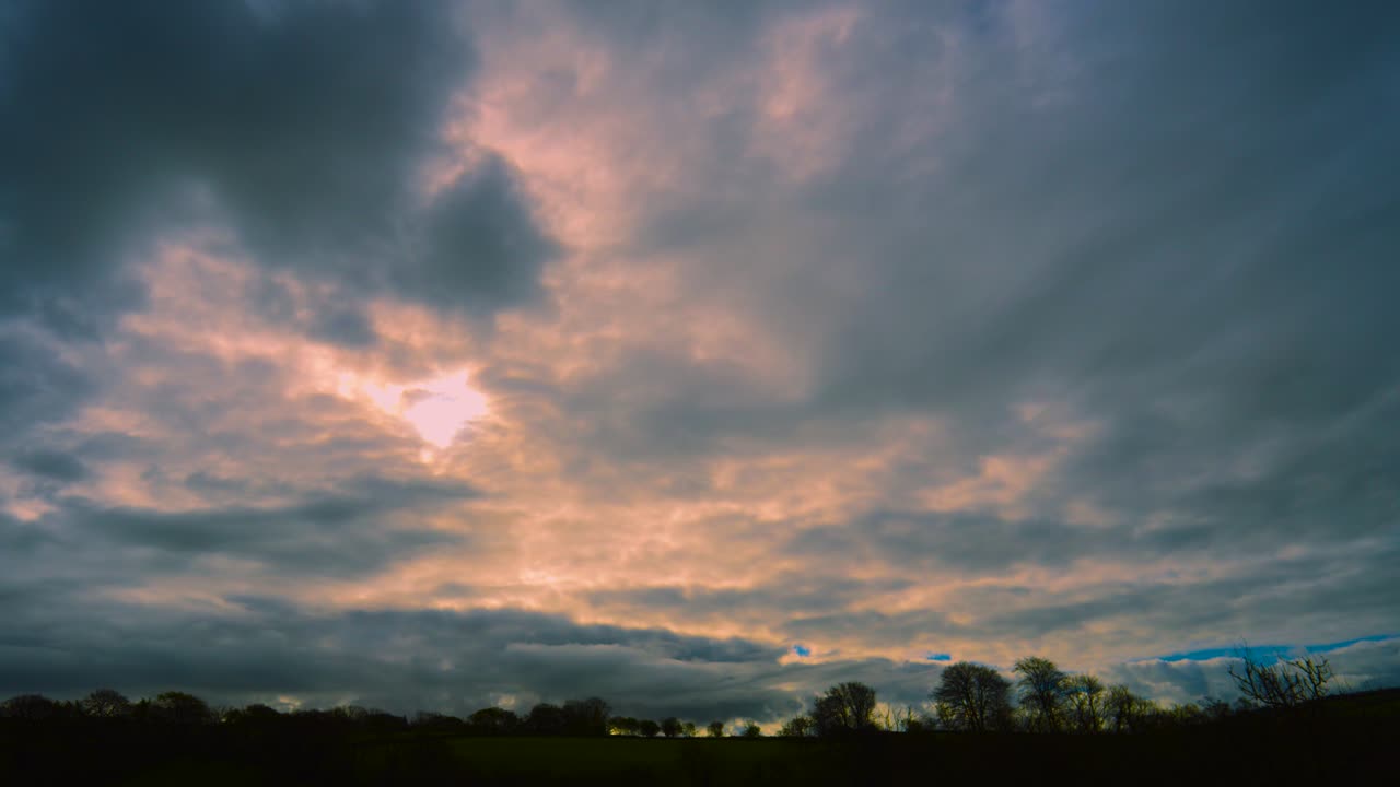 Landscape View of Fast Moving Timelapse with Bright Sunlight Behind Clouds with Trees Silhouetted on Horizon. Natural Background Wallpaper Copy Space.