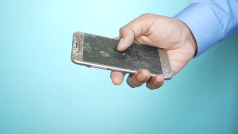 un primer plano de la mano de un hombre sosteniendo un teléfono inteligente roto.