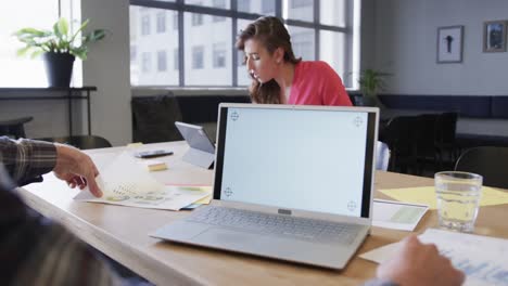 portátil con espacio de copia en la pantalla y diversos colegas en discusión en la oficina casual, cámara lenta