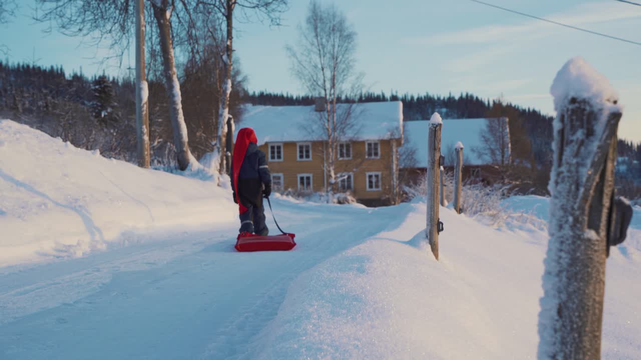 En liten gutt trekker en kjelke på en juledag om vinteren i Norge