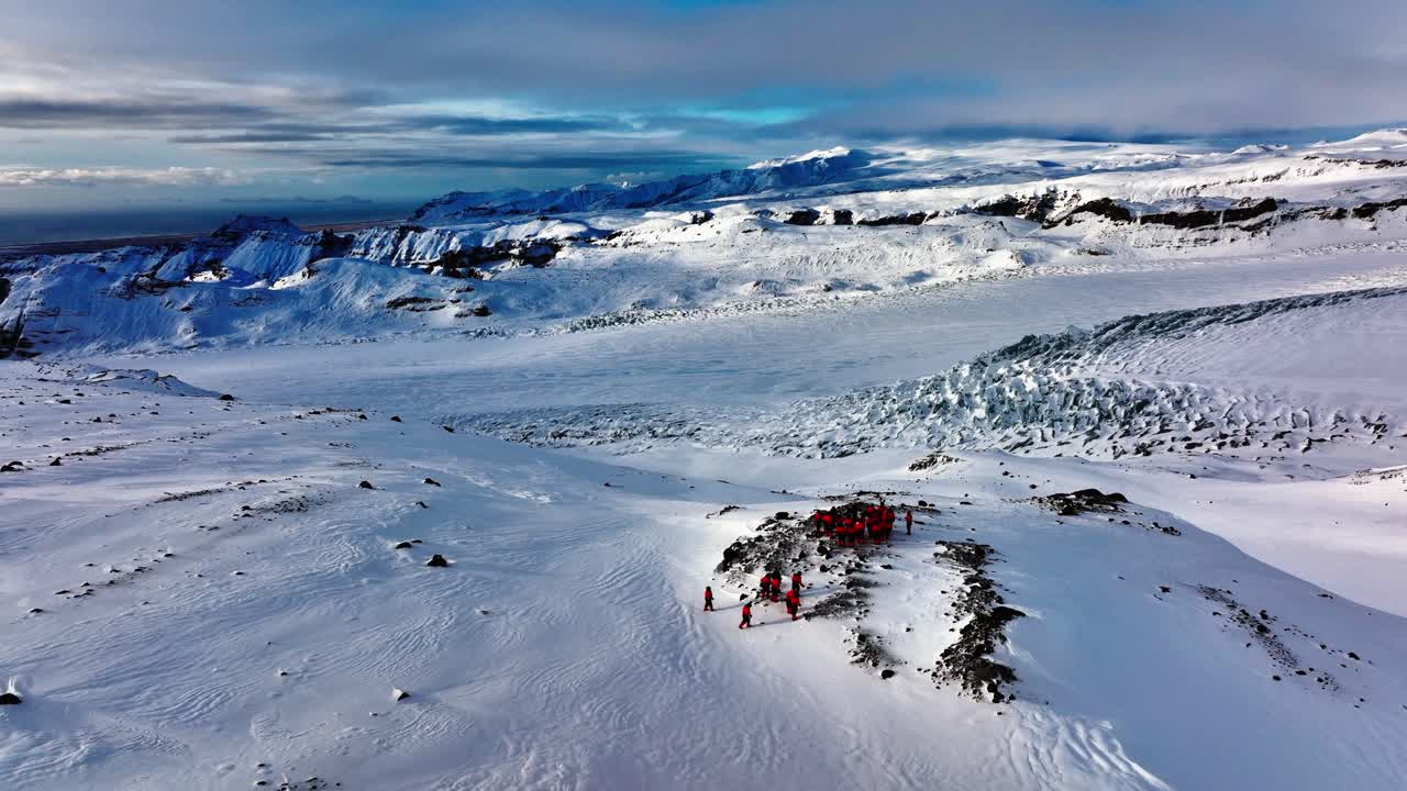 vista aérea de personas mirando el panorama del glaciar myrdalsjokull, después de montar motos de nieve en islandia, al anochecer
