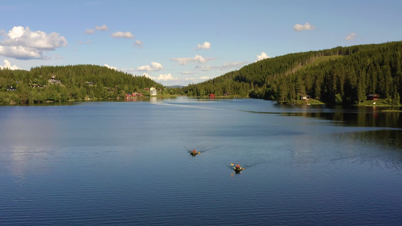 Two packrafts paddling on Mylla Lake surrounded by forest on stunning day, drone