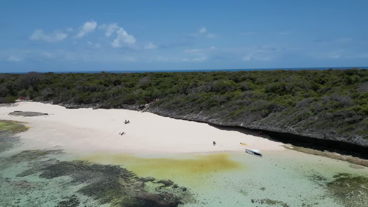 Sand bank on the rocky shores of Pungume Island Zanzibar Tanzania Africa with boats and people, Aerial dolly out shot