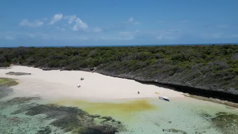 Sand-bank-on-the-rocky-shores-of-Pungume-Island-Zanzibar-Tanzania-Africa-with-boats-and-people,-Aerial-dolly-out-shot