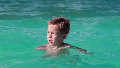 little boy bathing in clear blue sea