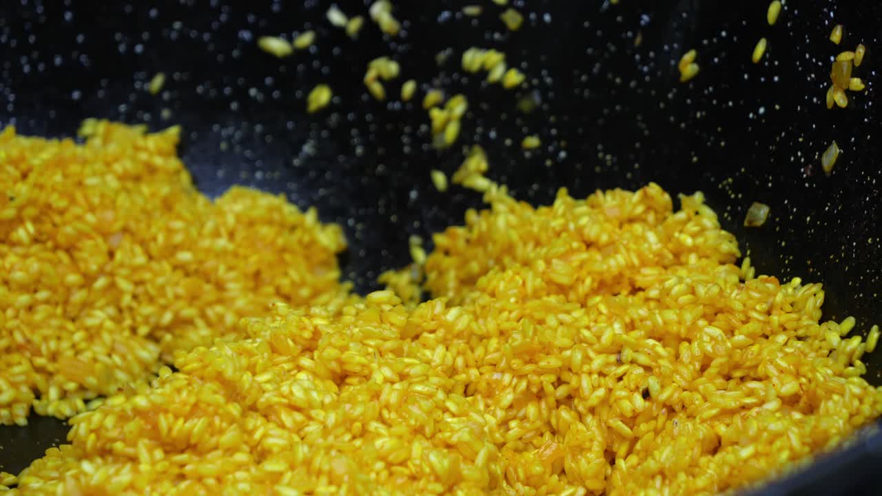 Yellow colored rice italian Risotto dish stirring