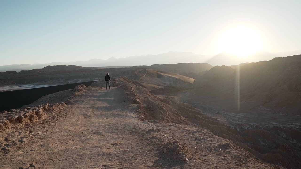 excursionista en cámara lenta caminando sobre una montaña al amanecer en el desierto