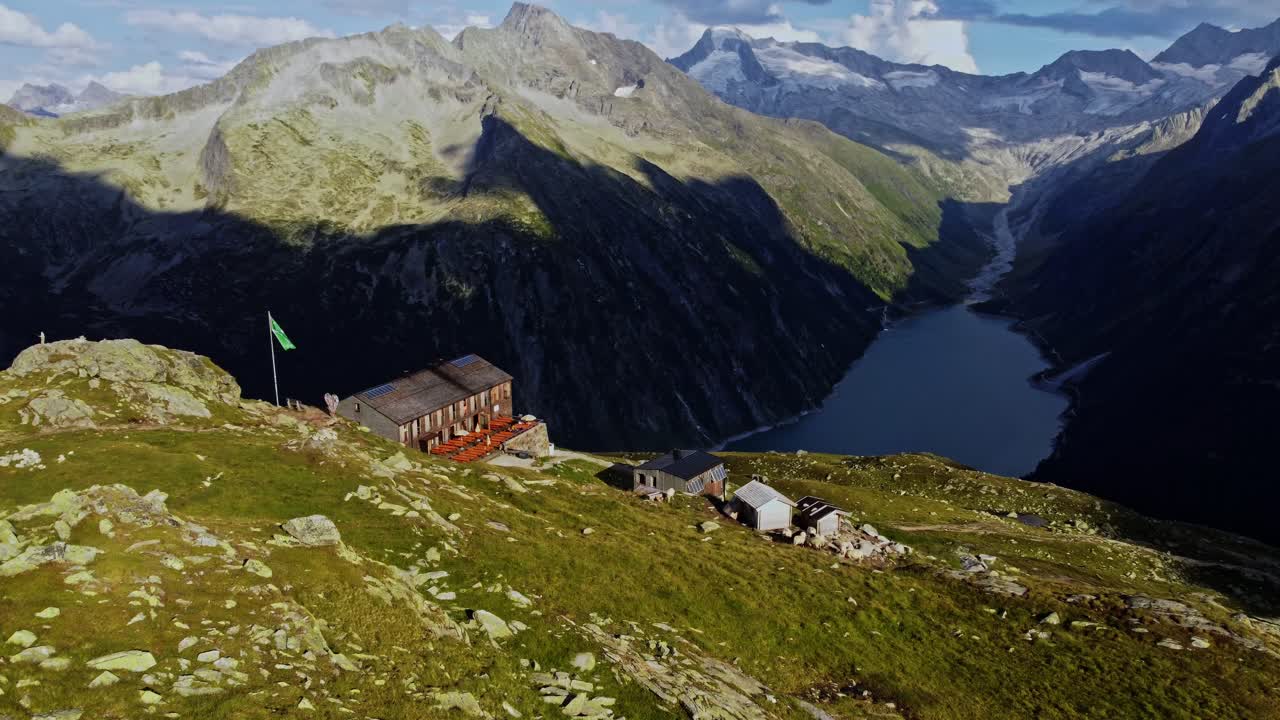 Orbit drone shot beautiful scenic view of European hut named "Olpererh&uuml;tte" in Austrian Alps in summer with the Schlegeis Stausee below