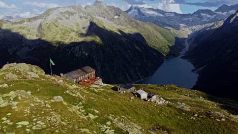 orbit drone shot beautiful scenic view of european hut named "olpererhütte" in austrian alps in summer with the schlegeis stausee below