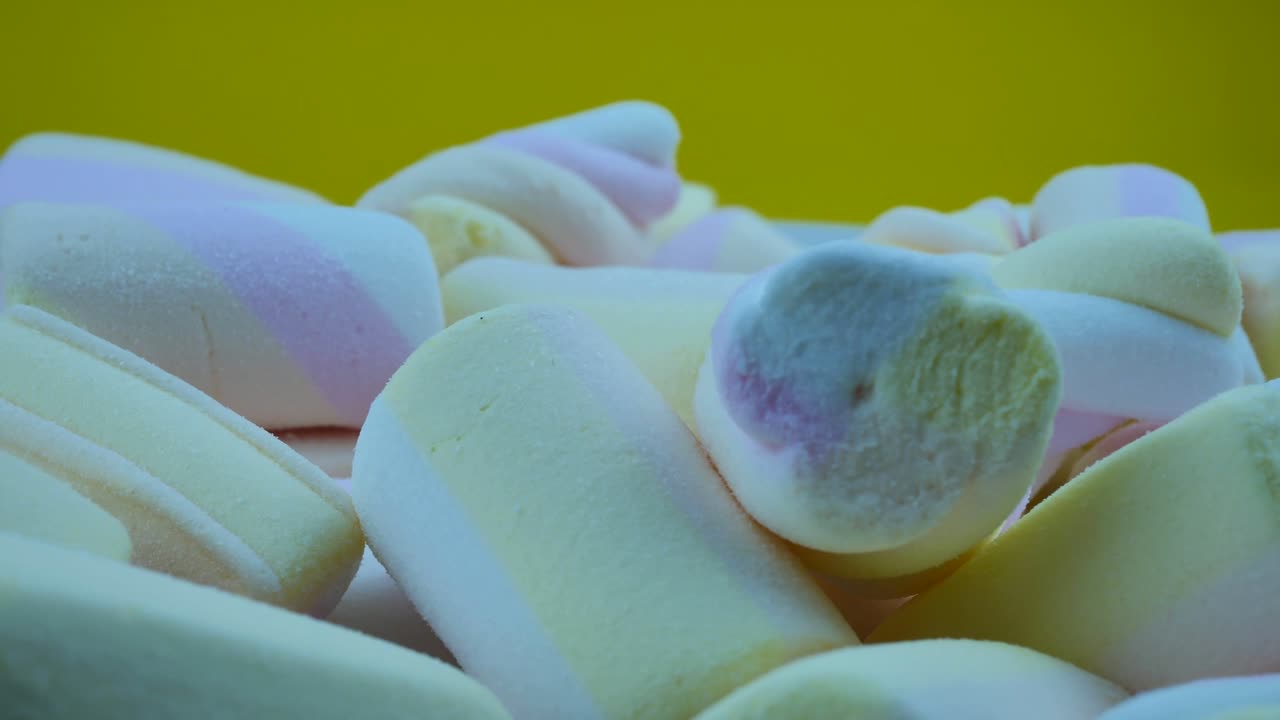 vista superior de muchos marshmallows retorcidos diferentes en fondo amarillo. concepto de comida de invierno
