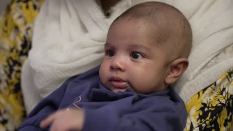 cute 2 month old bangladeshi infant looking curiously whilst held by mother