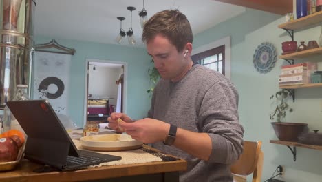 un hombre caucásico come el desayuno viendo una tableta con auriculares en los oídos