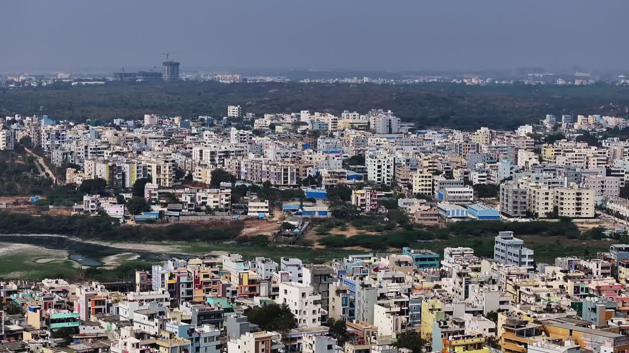 Edifici residenziali con lago prosciugato e foresta urbana a Suraram, Hyderabad, Telangana, India. Di giorno, carrellata, ripresa con drone, 4k