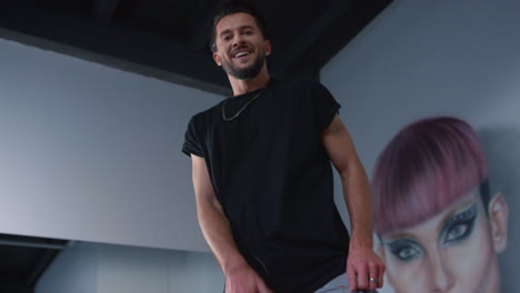 bailarina de estilo urbano mirando la cámara en la clase de baile. hombre sonriente bailando en el interior.
