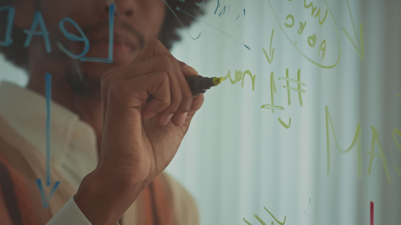 Black Male Entrepreneur Drawing Business Plan on Glass Wall at Office