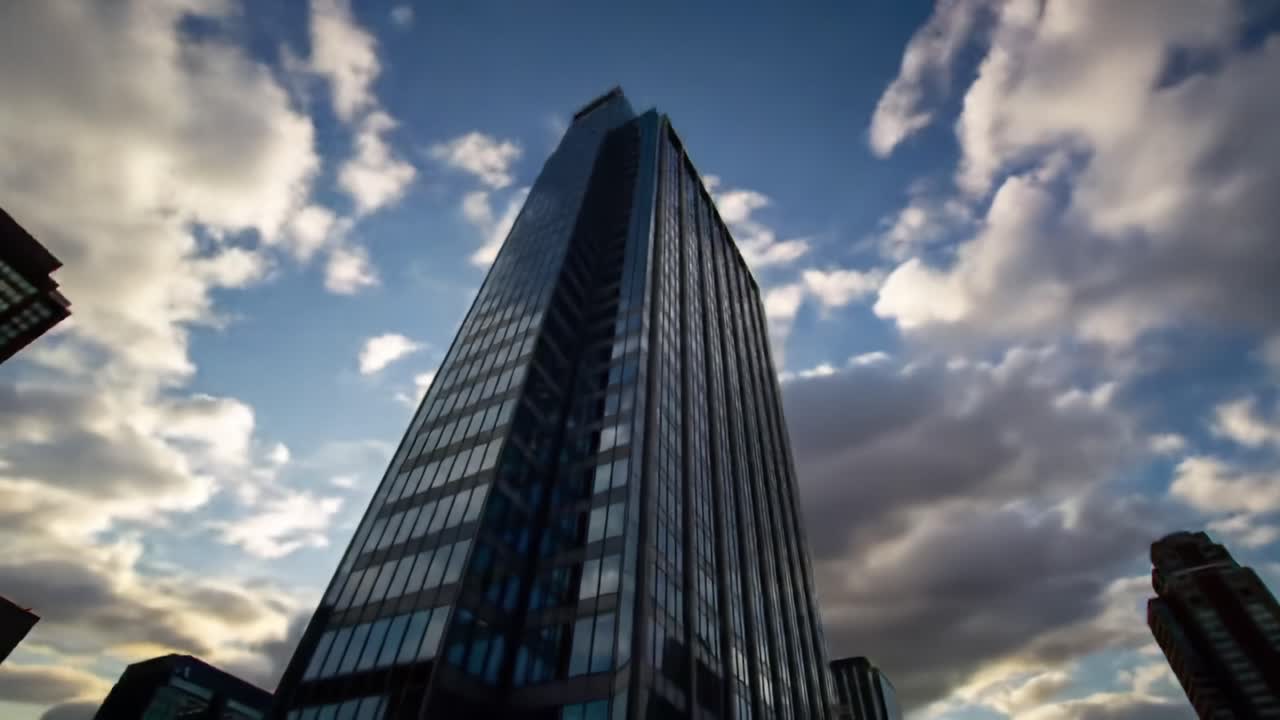 A Majestic Skyscraper Soaring Toward the Cloudy Sky: An Architectural Marvel with Reflective Glass and Dynamic Angles Capturing the Urban Skyline Beauty