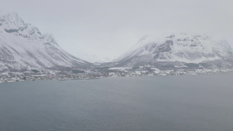 Aerial-drone-push-in-towards-snow-covered-Olderdalen,-Northern-Norway