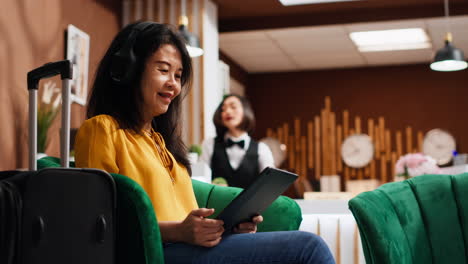 Asian-tourist-working-on-tablet-in-lounge-area-at-resort,